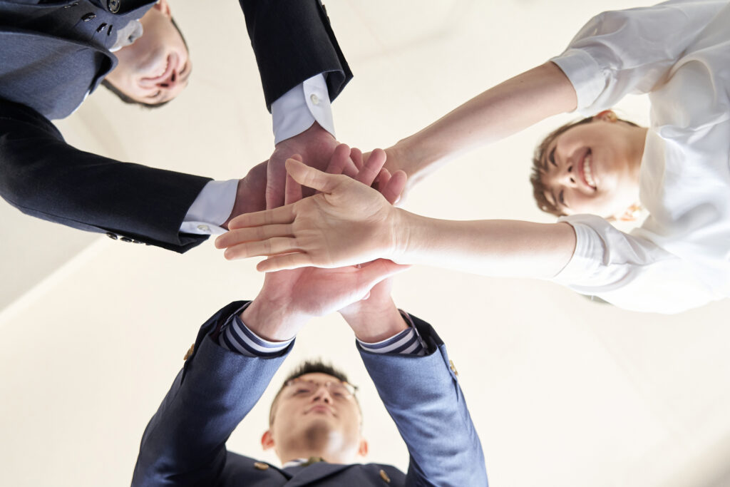 Group of salespeople putting their hands in to show teamwork with sales distribution